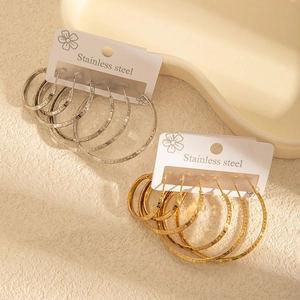 Détail macro de boucles d'oreilles créoles en acier avec motif grec en or et argent