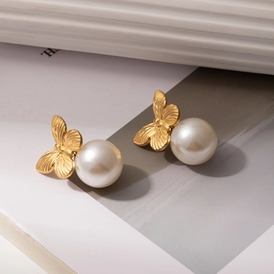 Detail of gold bow earrings with intricate wing texture and elegant white pearls
