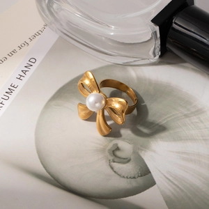 Elegant gold bow ring with center pearl and adjustable band in a lifestyle setting