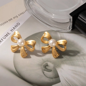 Detail of vintage gold bow earrings with lustrous white pearls on a lifestyle background