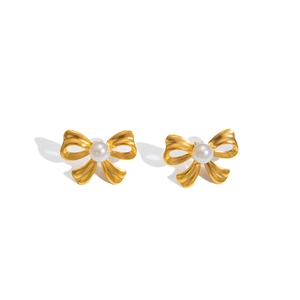 Detailed view of gold bow-shaped stud earrings featuring a central white pearl inlay