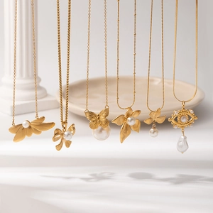 French vintage gold butterfly pearl necklace collection on white display pillars