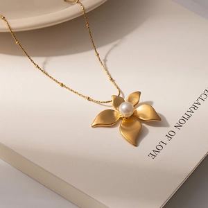 French vintage matte gold flower necklace with elegant pearl pendant on book