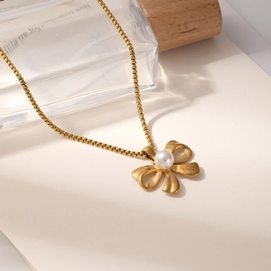 Detail of vintage gold bow necklace with central pearl and elegant box chain