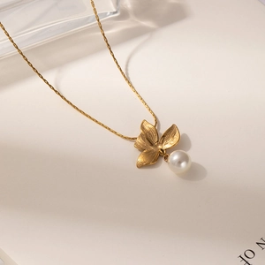 French vintage titanium steel necklace with matte flower and pearl pendant on a white book
