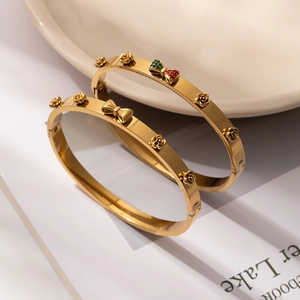 Detailed shot of gold titanium bracelets with 3D rose and rhinestone bow accents