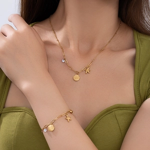 Dettaglio di collana e bracciale con ciondoli a stella marina e conchiglia indossati dal modello
