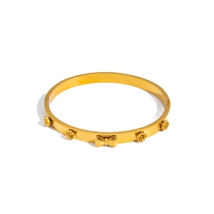 Detail of gold titanium steel bangle with 3D rose flowers and central bow design