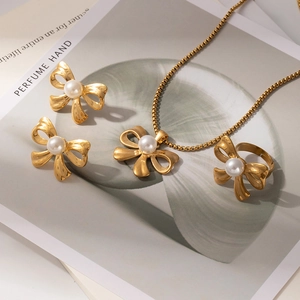 Detailed view of luxury gold bow and pearl jewelry set with necklace, earrings, and ring