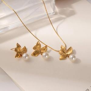 Detail of gold floral necklace and pearl earrings set with elegant pleated textures