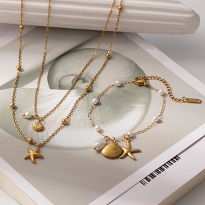 Dettaglio del set collana con stella marina e conchiglia dorata con perle in acciaio