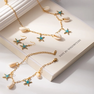 Dettaglio di parure di gioielli oceanici dorati con stelle marine blu e conchiglie bianche
