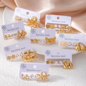 Golden stainless steel earring set with bow, clover, and zircon charms on display