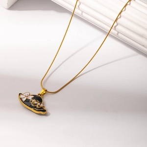 Detailed macro view of a gold snake chain with a black enamel hat pendant and pearls