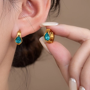 Close-up of teardrop blue zircon earrings in gold-plated steel on a female model