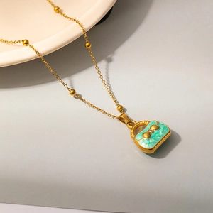 Detail of green handbag pendant necklace with gold bow and beaded chain for women