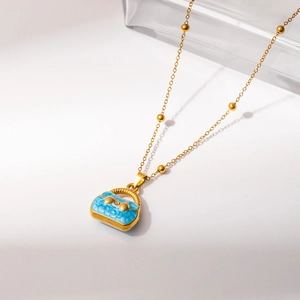 Detailed close-up of a gold necklace with light blue handbag pendant and floral enamel
