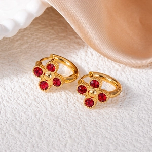 Dettaglio di orecchini a fiore in oro 18k con quadrifogli in zircone rosso brillante
