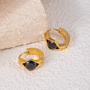 Detailed view of gold earrings with black round zircon in a geometric setting