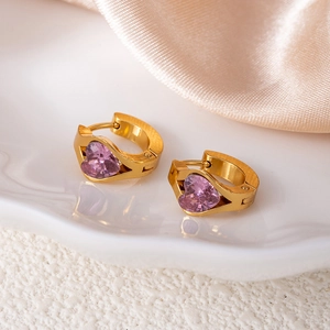 Detail of golden huggie earrings featuring a purple heart-shaped cubic zirconia stone