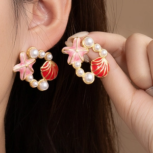 Vue macro de boucles d'oreilles étoile de mer en émail coloré avec perles