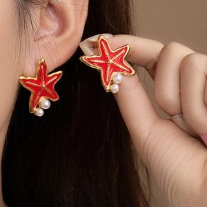 Vue détaillée de boucles d'oreilles étoile de mer rouge émaillée avec perles