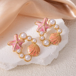 Détail de boucles d'oreilles étoile de mer dorées avec perles sur pierre blanche