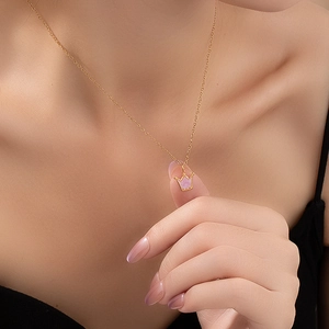Detailopname van een gouden ketting met roze kroonhanger gedragen door een model