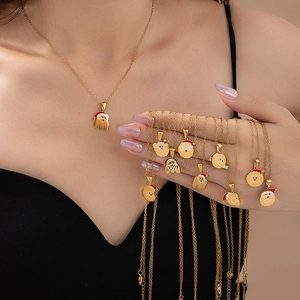 Détail de divers pendentifs Père Noël en émail rouge et blanc sur un collier doré en acier