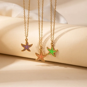 Detailopname van zeester hangers in paars, oranje en groen emaille aan gouden ketting