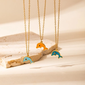 Detail van drie kleurrijke emaille dolfijn hangers aan fijne gouden kettingen