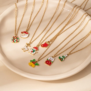Mise à plat de divers colliers de Noël avec breloques en émail sur un plateau en céramique