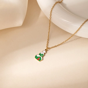 Gros plan d'un collier doré avec pendentif maison festive sur fond crème doux