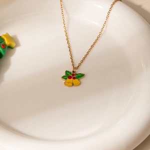 Détail du pendentif cloches de Noël dorées avec feuilles de houx et baies rouges