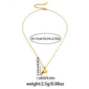 Détail macro du collier en acier doré avec pendentif de Noël en émail rouge