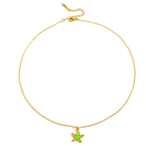 Close-up van gouden ketting met een groene zeester hanger en verfijnde gouden texturen