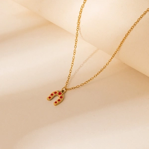 Detail of horseshoe pendant necklace with red heart accents on warm beige display