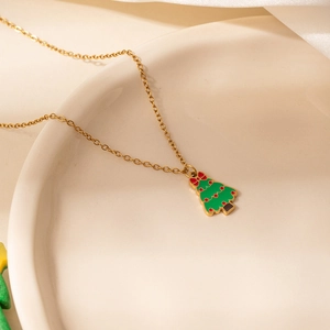 Détail du pendentif sapin de Noël en émail vert et nœud rouge sur chaîne dorée