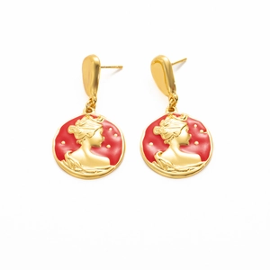 Macro detail of French vintage gold earrings with red enamel and queen portrait relief