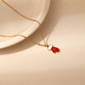 Detail shot of a red Christmas glove pendant with golden snowflake on a fine gold chain