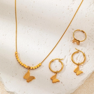 Golden butterfly jewelry set with necklace earrings and ring on a marble stone base