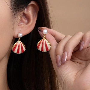 Chic gold-plated shell earrings with red stripes and pearl studs on model ear