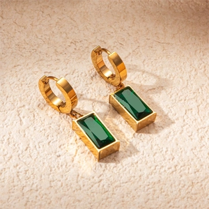Detailed close-up of gold-plated earrings featuring emerald green rectangular zircons