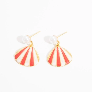 Detailed view of gold shell earrings featuring red enamel stripes and white pearl studs