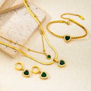 Close-up of gold butterfly jewelry set with green heart stones and steel engraving