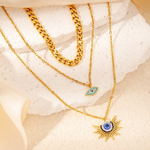Vue macro de colliers dorés superposés avec pendentifs œil bleu sur pierre et soie