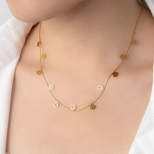 Close-up of golden necklace featuring hollow rose pendants worn on a woman's neck