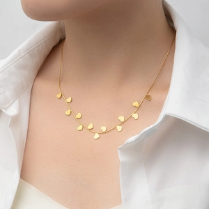 Close-up of a gold minimalist necklace featuring multiple heart charms on a delicate chain
