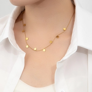 Detail view of a gold honeycomb necklace with hexagonal charms on a female model