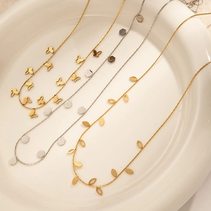 Detailed macro view of gold butterfly, silver hex, and leaf pendant necklaces on ceramic
